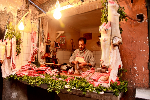 Butcher working by the light of some brightly strung bulbs.