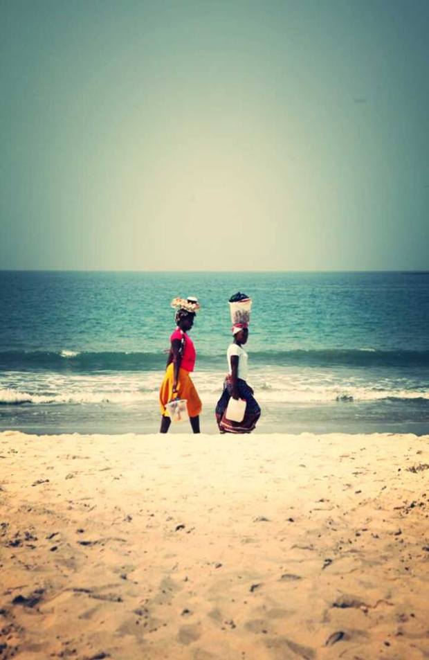 Two women walk as the sun sets on Tokeh Beach in Sierra Leone